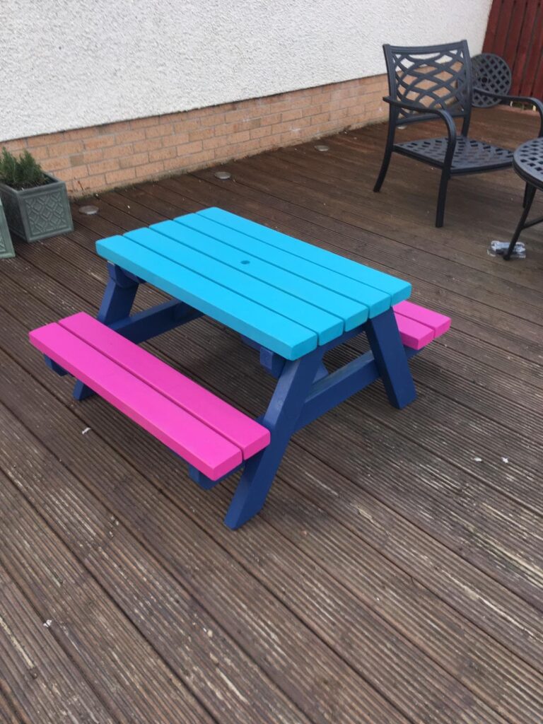 blue and pink painted kids picnic table in a back garden